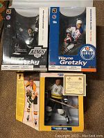 Two Wayne Gretzky hockey figures in boxes: Edmonton Oilers and Los Angeles Kings versions, and one Bobby Orr figure in Boston Bruins uniform with certificate of authenticity.