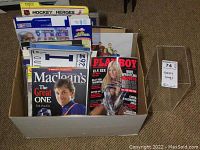 Box with a variety of hockey magazines, collectible items including a signed Playboy magazine with WWE Torrie Wilson cover, a Vince Carter Cocoa Frosted Flakes box, and historic sports memorabilia.