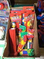 Box with multiple unopened PEZ candy dispensers including Disney characters and assorted candy refills.