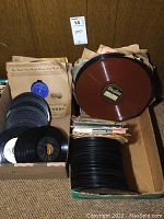 Boxes and stacks of vintage 45 RPM and 78 RPM records, some brown colored vinyl, mostly without sleeves showing wear