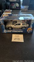 Front view of unopened Welly 1:24 scale Back to the Future DeLorean Time Machine in original packaging showing side profile of silver car with 'Time Machine' text on box.