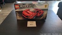 Front view of the unopened Lego Speed Champions Ferrari F8 Tribute box on a table, showing the Ferrari sports car image and Lego branding.