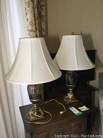 Two matching table lamps with brass bases and ribbed amber glass bodies topped with cream fabric bell-shaped shades.
