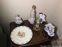 Overview of six collectibles on table including plate and figurines