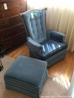 Velveteen swivel armchair and ottoman set photographed in a room next to wooden dresser and curtains. Shows chair's front and ottoman beside it.