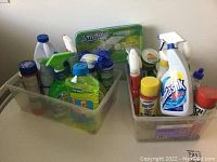 First photo showing two plastic containers filled with multiple cleaning products such as sprays, liquid soap, and wipes.
