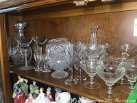 Wide view of the cabinet shelf with the decanter, various glasses, and vases.