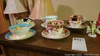All five teacup sets and miniature figurine on surface