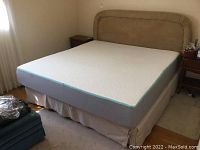 Full view of king size bed with Endy memory foam mattress on beige box spring and upholstered headboard, showing overall condition and setup.