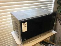 Outer view of Panasonic microwave oven showing black exterior with digital control panel and ventilation grates on side.