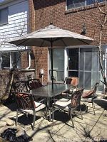 Full set view showing table, six chairs and umbrella in patio setting