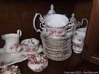 Coffee pot, tea pot, stack of plates with two-handle soup bowl on top, cream pitcher and sugar bowl visible