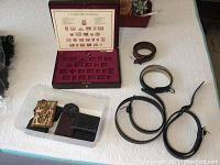 Overview of three men's belts and the wooden stamp collector's box with compartments and key
