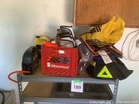 Overall view of car emergency and maintenance items on shelf with crates and bags.