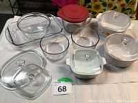 Photo showing multiple Corning Ware and glass containers with lids on a table.