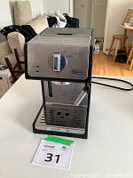 Full view of DeLonghi espresso machine with stainless steel finish and milk frother wand attached.