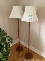 Two matching teak floor lamps side by side showing full height, bases and shades