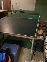 Full view of folding ping pong table set up for play in basement or storage area.