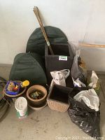 Photo showing various gardening supplies including bags of mulch, lime, planters of different sizes and materials, green winter plant covers, and bamboo sticks.