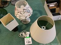 Two table lamps on carpet with a replacement white lampshade and clamp-on light. One lamp has a silver base with a white embroidered floral shade. The other has a dark wood base and a plain white square shade.