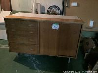 Front view of the wooden cabinet showing side with drawers and sliding doors.