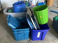 Photo showing a blue Rubbermaid bin with matching lids stacked inside, a green round bin, purple bin, and a large gray bin with a blue tarp inside.