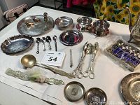 Photo showing overall assortment of silver-plated trays, spoons, ladles, small bowls, and a boxed set of teaspoons.