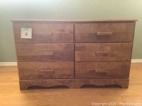 Front view of the dresser showing six drawers with rectangular wood handles and natural wood finish.