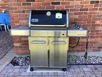 Front view of Weber Genesis BBQ showing hood, side shelves and cabinet