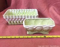 Two pale chartreuse ceramic vases, one rectangular with basket weave pattern and one smaller with oval relief sides, both with white drip glaze detail.