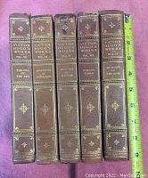 Front view of the spines of five leather bound Victor Hugo books showing titles and volume numbers.