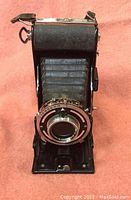 Front view showing lens, bellows, and folding mechanism on antique camera