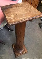 Full view of antique pine pedestal showing square top, cylindrical column, and base.