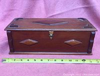 Front view of the wooden dresser box showing diamond point design, lock clasp, and measuring tape indicating size