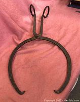 Top-down image of large hand wrought iron ice tongs showing overall shape and curved gripping ends