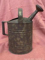 Front and side view of a rusty galvanized steel watering can with angled spout and handle.