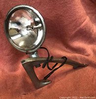 Front view of vintage marine spotlight showing reflective interior and mount base on fabric background.