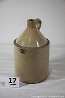 Full view of off-white stoneware jug with handle and narrow neck