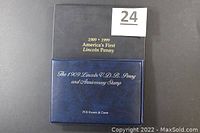 Closed view of Set 2 navy blue folder with gold lettering: '1909 - 1999 America's First Lincoln Penny' and 'The 1909 Lincoln V.D.B. Penny and Anniversary Stamp',' PCS Stamps & Coins.'