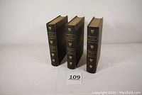 Three leather bound volumes of Our Country by Benson J. Lossing standing upright, showing black leather covers with gold marks.