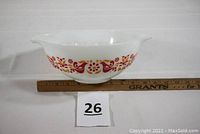 Side view of Pyrex mixing bowl with Friendship pattern showing red birds and orange floral elements with a measuring ruler for scale.