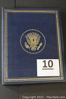 Closed blue presentation case with gold presidential seal on cover