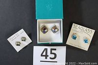 Photo showing the three sets of stud earrings: blue seaglass sterling silver earrings on the right, multi-colored square earrings in the middle, and green studs on the left attached to a note indicating AJ 925 14KT.