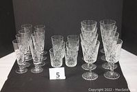 Three groupings on black background: 8 champagne flutes at left, 6 tumblers center, 8 wine goblets right