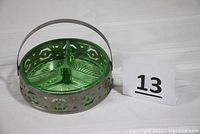 Image showing full dish with three-section green glass inside metal basket and handle on top.