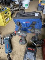 Three tools, charger, and carrying bag laid on floor
