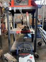 Photo of black metal utility cart with mounted power tool and electrical cord wound on side hook.