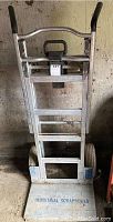Front view of dolly showing aluminum frame, black rubber handles, and label with lot number