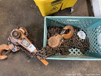 Photo of the 6 ton chain hoist and heavy steel chain inside a green plastic bin on a concrete floor.