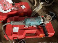 Makita GA7050 blue angle grinder placed on top of a red Milwaukee tool case, showing top and side views.